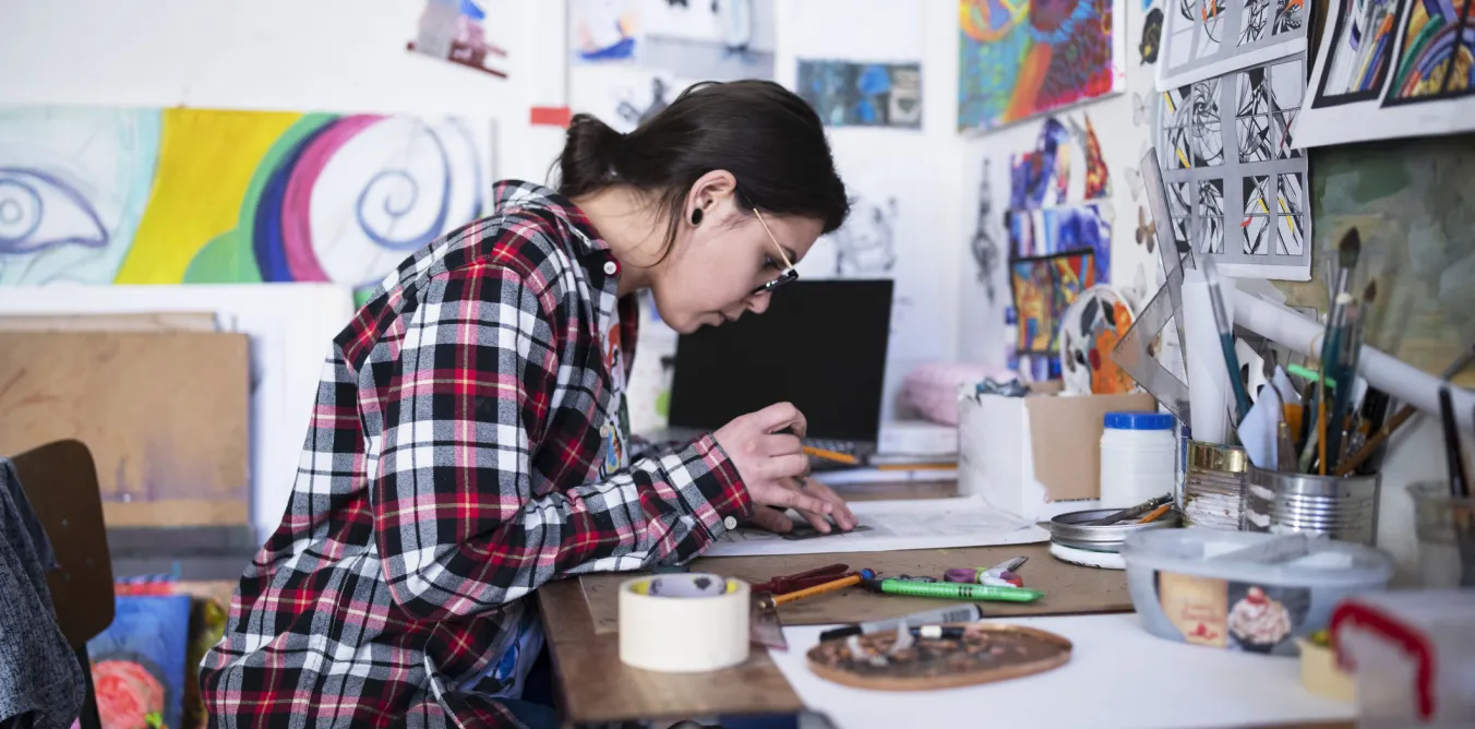 Student creating art at a desk