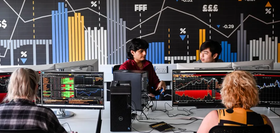 Photo of students at the University of Suffolk's Bloomberg Lab, with charts on screens and graphs on the wall. Image credit: Gregg Brown Photography / University of Suffolk.