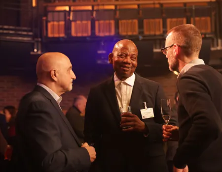 Three men in suits talking together and smiling