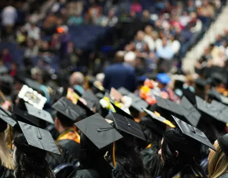 A group of graduates at their ceremony, showing the backs of their caps