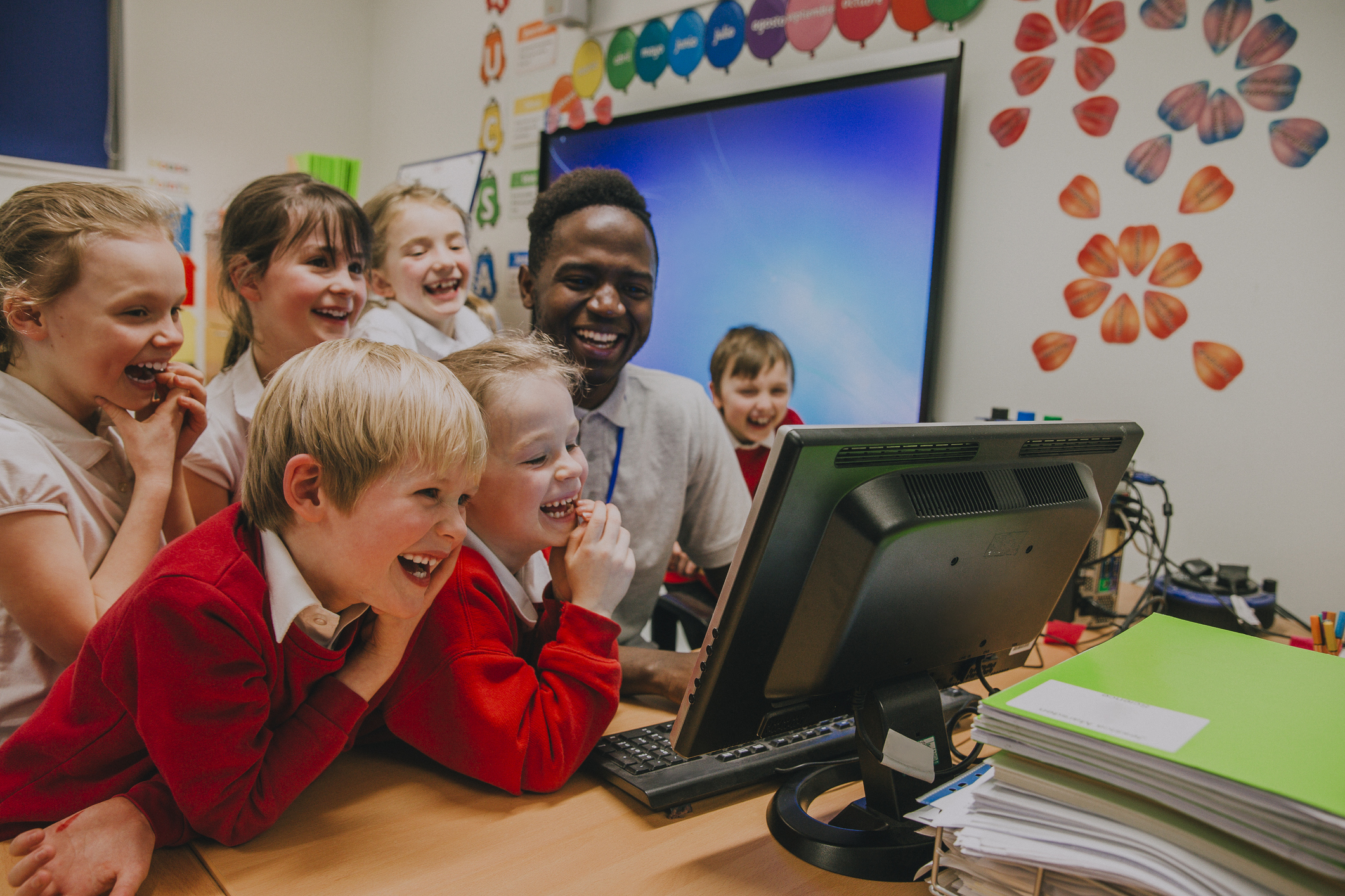 Photo of teacher with children looking at computer